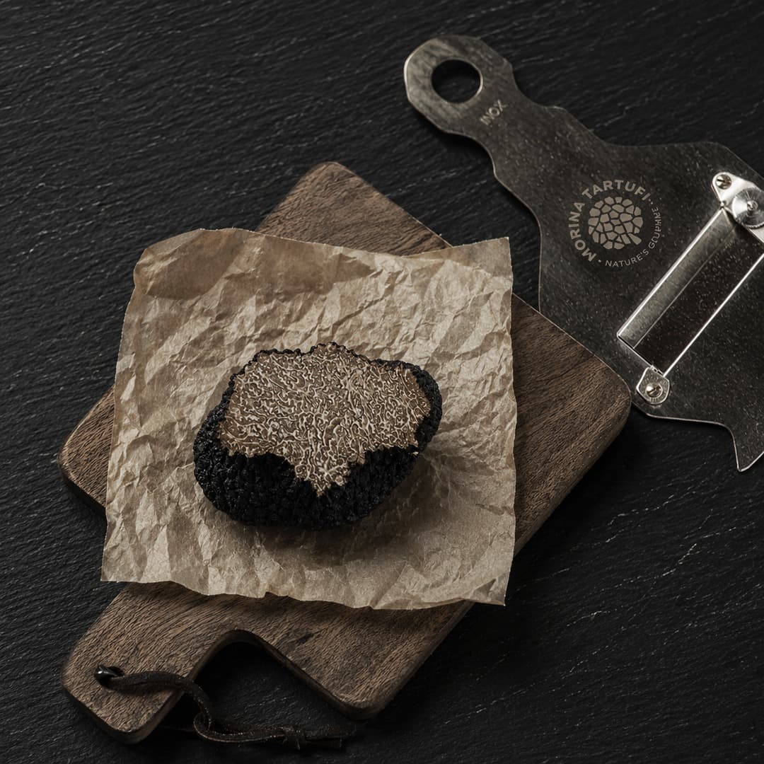 Black truffle sliced on wooden board with Morina slicer